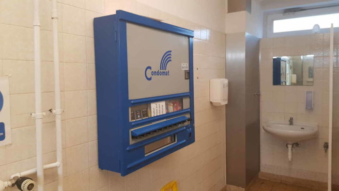 An der Wand hängt ein blauer Kondomautomat