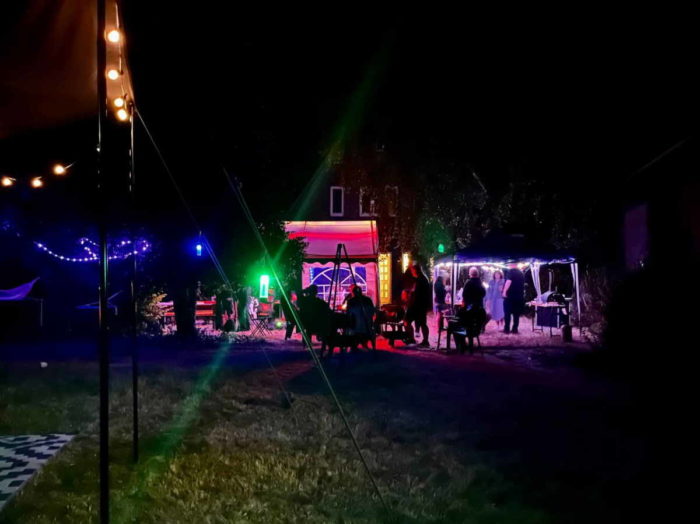 Unser Garten am Freitagabend: Es ist dunkel, Lichterketten beleuchten ein Partyzelt und einen Pavillon. Darunter sind aus der Entfernung Menschen zu sehen. (Foto von Inga)