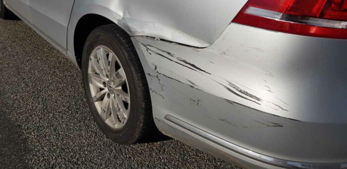 Nahaufnahme der beschädigten Stelle an unserem Auto. Der Kotflügel und ein Teil der Stoßstange sind deformiert und stark verkratzt.