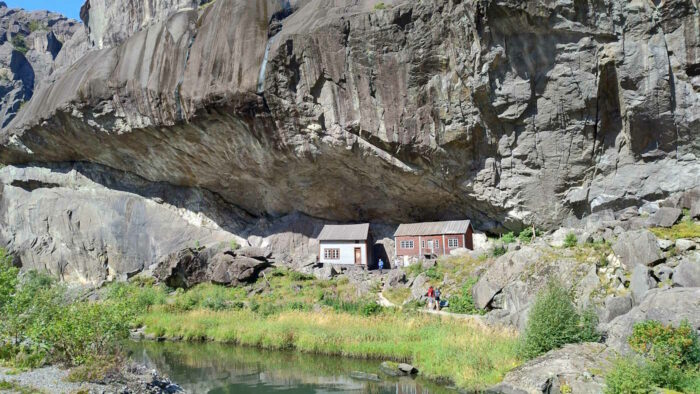 Die Helleren im Jøssingfjord sind alte Häuser, die kein Dach brauchten, weil sie unter einem Felsvorsprung gebaut wurden. Man erkennt anhand von sehr klein ausshenden Menschen, wie unglaublich groß dieser Felsvorsprung ist.