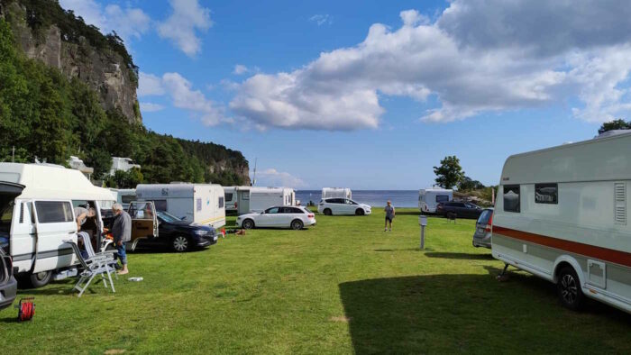 Unser Campingplatz in Rognstranda. In der Bildmitte ist das Meer zu sehen, links hinter den Wohnwagen ragt eine Felswand steil in den Himmel.